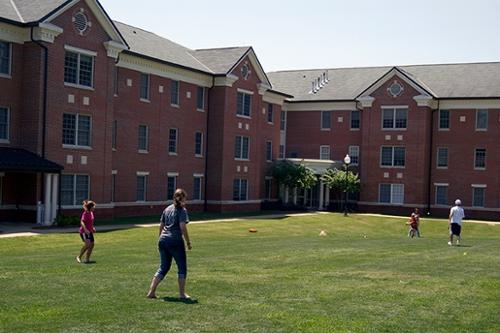 Exterior view of Hawkins Hall with students playing softball in the foreground
